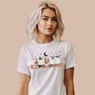 White t-shirt featuring a row of dogs dressed in ghost costumes with pumpkins, perfect for Halloween fun and dog lovers.