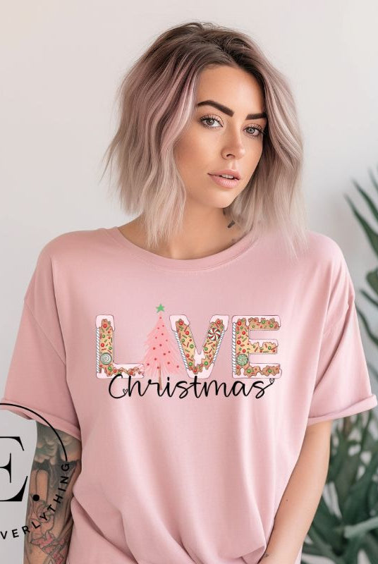 Get ready to celebrate the holiday season in style with our Christmas shirt featuring cute gingerbread cookies arranged to spell out the word "Love" on a pink colored shirt. 