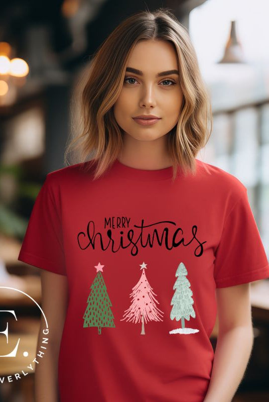 Elevate your festive wardrobe with our trendy shirt and make a chic statement this Christmas. The design features a stylish "Merry Christmas" message along with modern pink and teal Christmas trees, adding a fresh twist to the holiday season on a red shirt. 