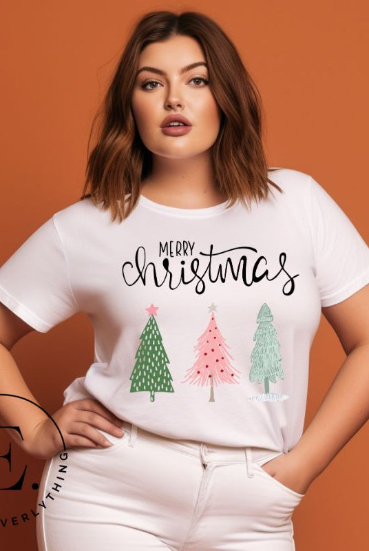 Elevate your festive wardrobe with our trendy shirt and make a chic statement this Christmas. The design features a stylish "Merry Christmas" message along with modern pink and teal Christmas trees, adding a fresh twist to the holiday season on a white shirt. 