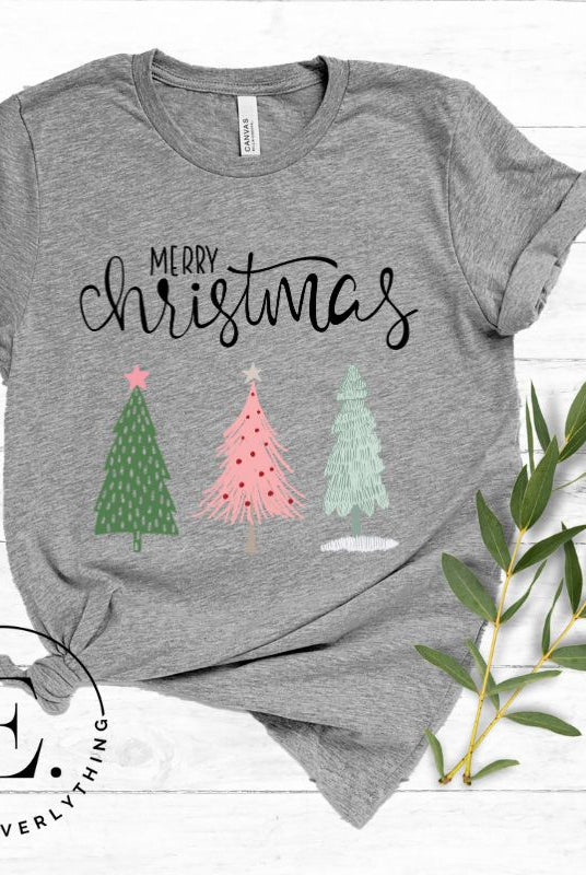 Elevate your festive wardrobe with our trendy shirt and make a chic statement this Christmas. The design features a stylish "Merry Christmas" message along with modern pink and teal Christmas trees, adding a fresh twist to the holiday season on a grey shirt.