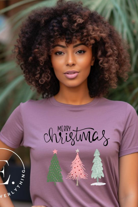 Elevate your festive wardrobe with our trendy shirt and make a chic statement this Christmas. The design features a stylish "Merry Christmas" message along with modern pink and teal Christmas trees, adding a fresh twist to the holiday season on a purple shirt.