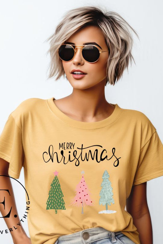 Elevate your festive wardrobe with our trendy shirt and make a chic statement this Christmas. The design features a stylish "Merry Christmas" message along with modern pink and teal Christmas trees, adding a fresh twist to the holiday season on a yellow shirt.