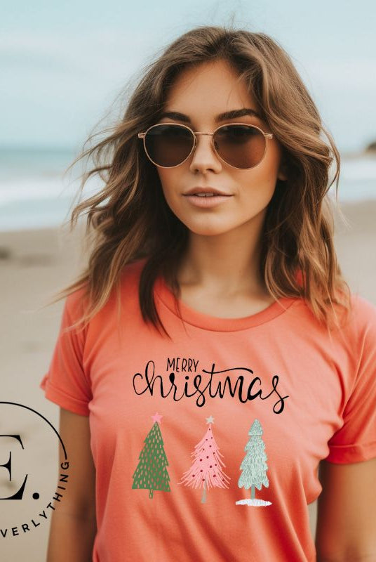 Elevate your festive wardrobe with our trendy shirt and make a chic statement this Christmas. The design features a stylish "Merry Christmas" message along with modern pink and teal Christmas trees on a peach shirt.