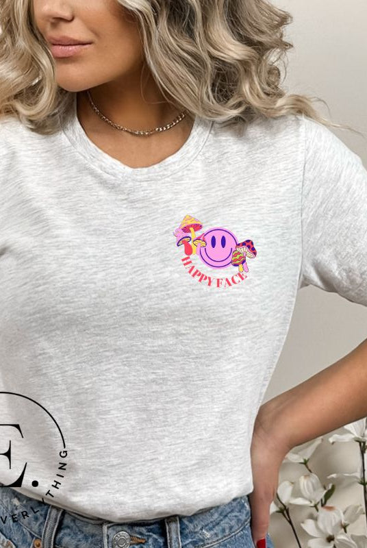 Spread positivity with our delightful t-shirt. The design features a happy face with mushrooms on the side and the words 'Happy Face' on the front pocket on a grey shirt. 