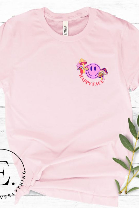 Spread positivity with our delightful t-shirt. The design features a happy face with mushrooms on the side and the words 'Happy Face' on the front pocket on a pink shirt. 