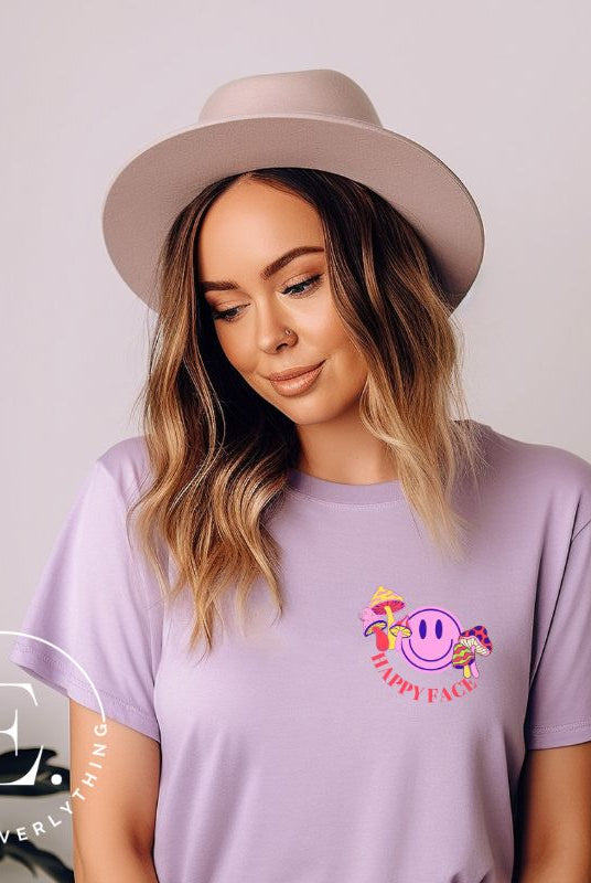 Spread positivity with our delightful t-shirt. The design features a happy face with mushrooms on the side and the words 'Happy Face' on the front pocket on a purple shirt. 