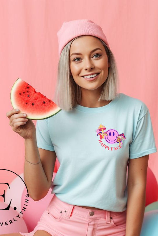 Spread positivity with our delightful t-shirt. The design features a happy face with mushrooms on the side and the words 'Happy Face' on the front pocket on an ice blue shirt. 
