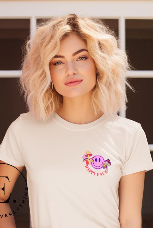 Spread positivity with our delightful t-shirt. The design features a happy face with mushrooms on the side and the words 'Happy Face' on the front pocket on a tan shirt. 