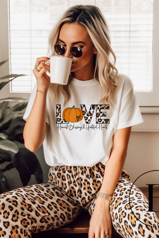 Spread love and autumn vibes with our trendy t-shirt. Featuring the word 'love' in cheetah print with a pumpkin as the 'o,' and "Harvest Blessings and Grateful Hearts' underneath on a white shirt. 