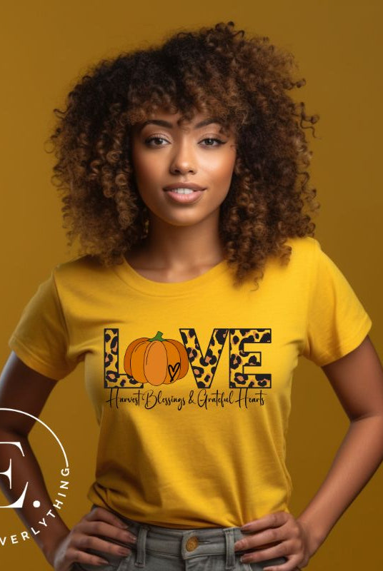 Spread love and autumn vibes with our trendy t-shirt. Featuring the word 'love' in cheetah print with a pumpkin as the 'o,' and "Harvest Blessings and Grateful Hearts' underneath on a yellow shirt. 