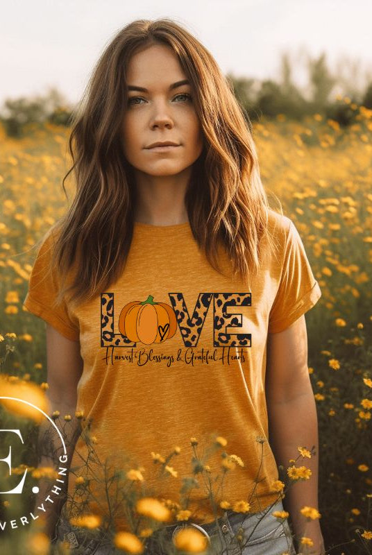Spread love and autumn vibes with our trendy t-shirt. Featuring the word 'love' in cheetah print with a pumpkin as the 'o,' and "Harvest Blessings and Grateful Hearts' underneath on a heather orange shirt. 
