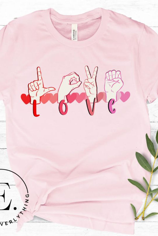 Beautiful ASL hand gesture spelling out love with hearts on a pink colored shirt.