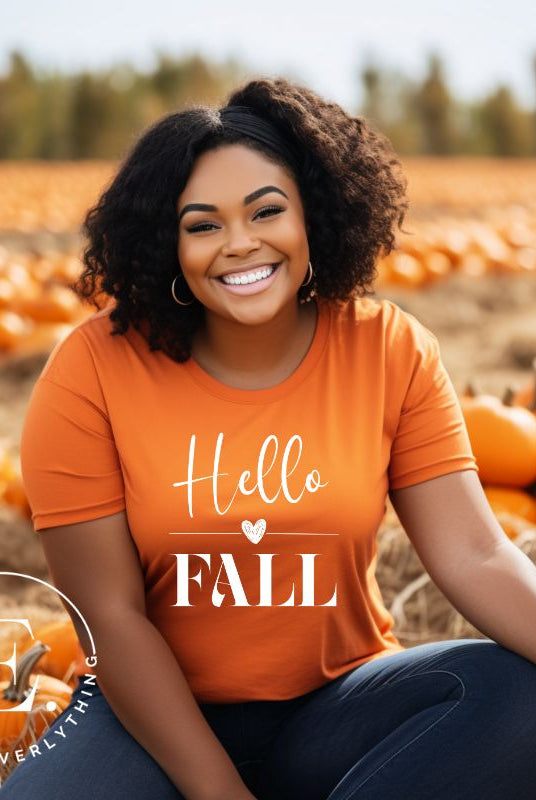 Hello Fall with heart between Hello and Fall graphic tee on a orange shirt.