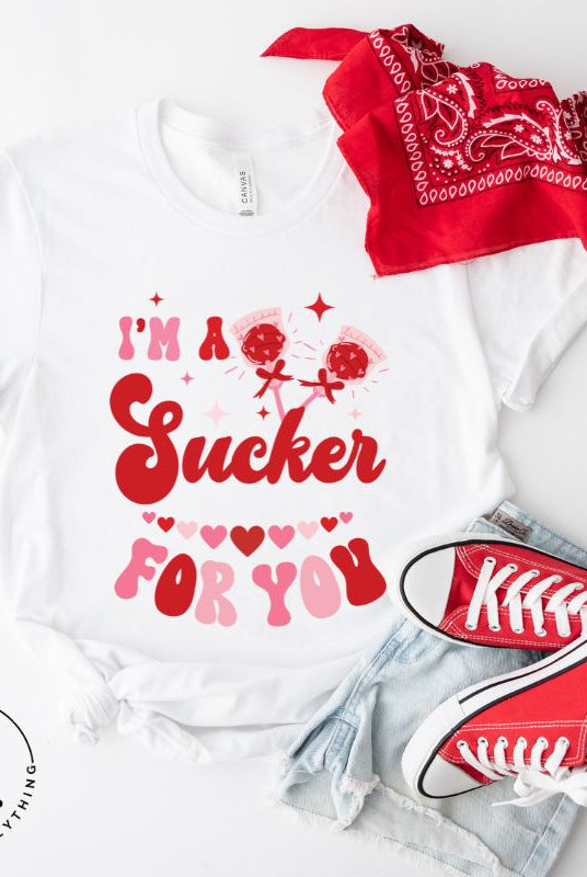 Indulge in the spirit of love with our Valentine's Day shirt! Adorned with charming Valentine lollipops and the playful saying, "I'm a sucker for you," on a white shirt. 