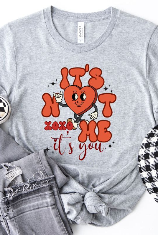 Celebrate Valentine's with our playful shirt! Featuring a bold heart and the message "It's not me, it's you," on a grey shirt. 