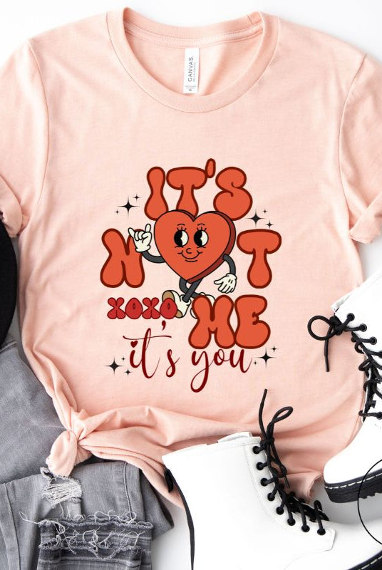 Celebrate Valentine's with our playful shirt! Featuring a bold heart and the message "It's not me, it's you," on a peach shirt. 