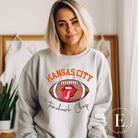 Show off your Kansas City pride with our exclusive sweatshirt that features the team's name and the spirited slogan, "Tomahawk Chop." On a grey sweatshirt. 