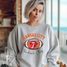 Show off your Kansas City pride with our exclusive sweatshirt that features the team's name and the spirited slogan, "Tomahawk Chop." On a grey sweatshirt. 