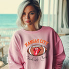 Show off your Kansas City pride with our exclusive sweatshirt that features the team's name and the spirited slogan, "Tomahawk Chop." On a pink sweatshirt. 