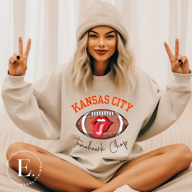 Show off your Kansas City pride with our exclusive sweatshirt that features the team's name and the spirited slogan, "Tomahawk Chop." On a sand colored sweatshirt. 