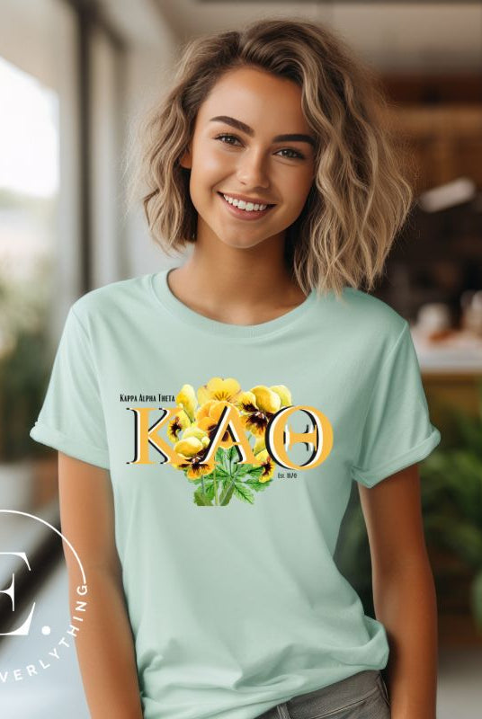 Show your Kappa Alpha Theta pride with our sorority t-shirt! Our design features the sorority letters and a striking black and gold pansy, symbolizing sisterhood and strength on a mint shirt. 
