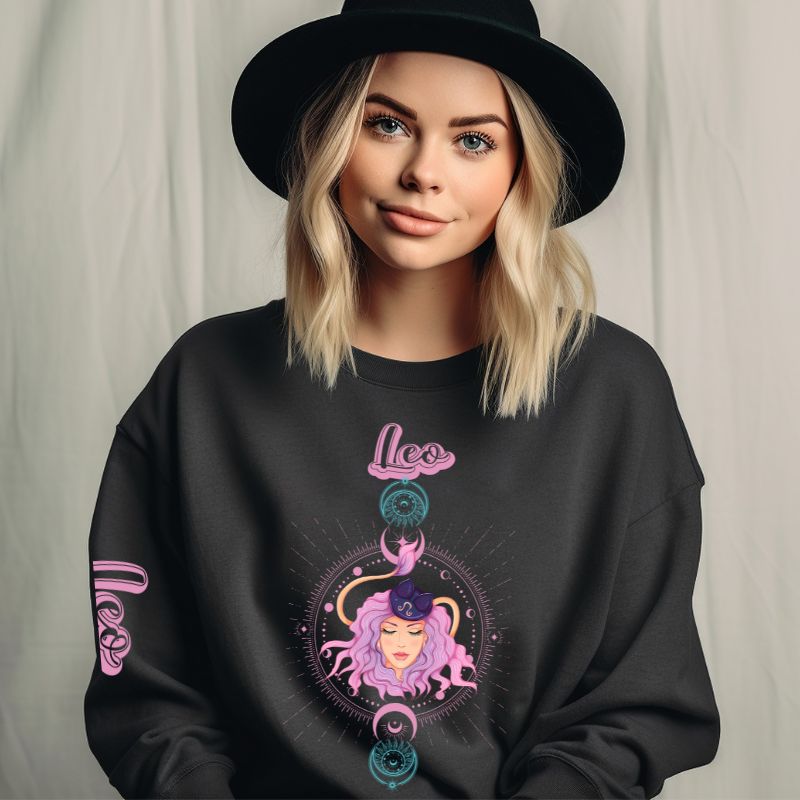 Gildan crewneck pullover sweatshirt featuring a pastel illustration of a Leo figure with flowing purple hair, surrounded by celestial elements. The word "Leo" is written in pink on the sleeve, adding a stylish touch on a dark grey sweatshirt.