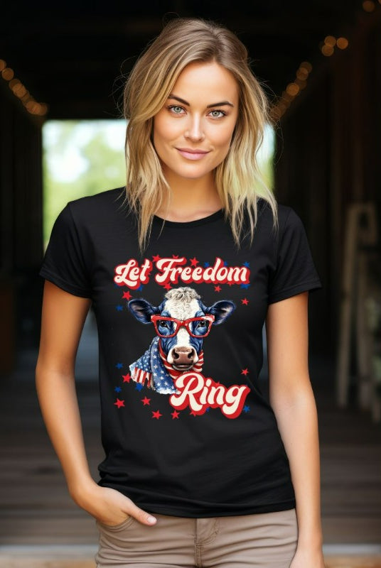 Graphic of a cow wearing sunglasses and a USA-themed scarf, with the text 'Let Freedom Ring' on the front of a black graphic tee.