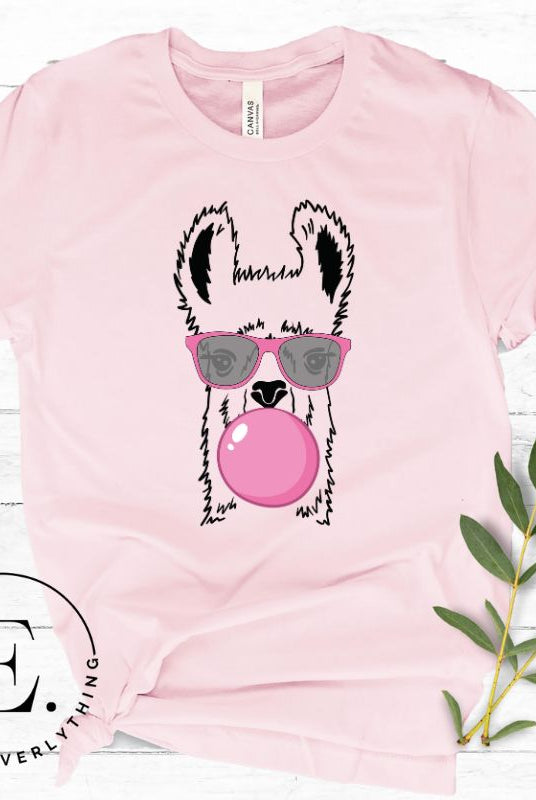 Llama wearing pink sunglasses blowing a bubble gum bubble on a light pink colored shirt.