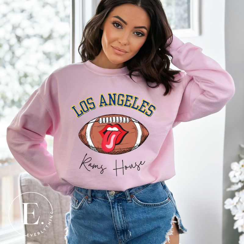 Cheer on the Los Angeles Rams in style with our exclusive sweatshirt featuring the team name and iconic slogan, "Ram House." On a pink sweatshirt. 