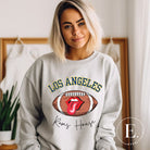 Cheer on the Los Angeles Rams in style with our exclusive sweatshirt featuring the team name and iconic slogan, "Ram House." On a grey colored sweatshirt. 