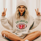 Cheer on the Los Angeles Rams in style with our exclusive sweatshirt featuring the team name and iconic slogan, "Ram House." On a sand colored sweatshirt. 