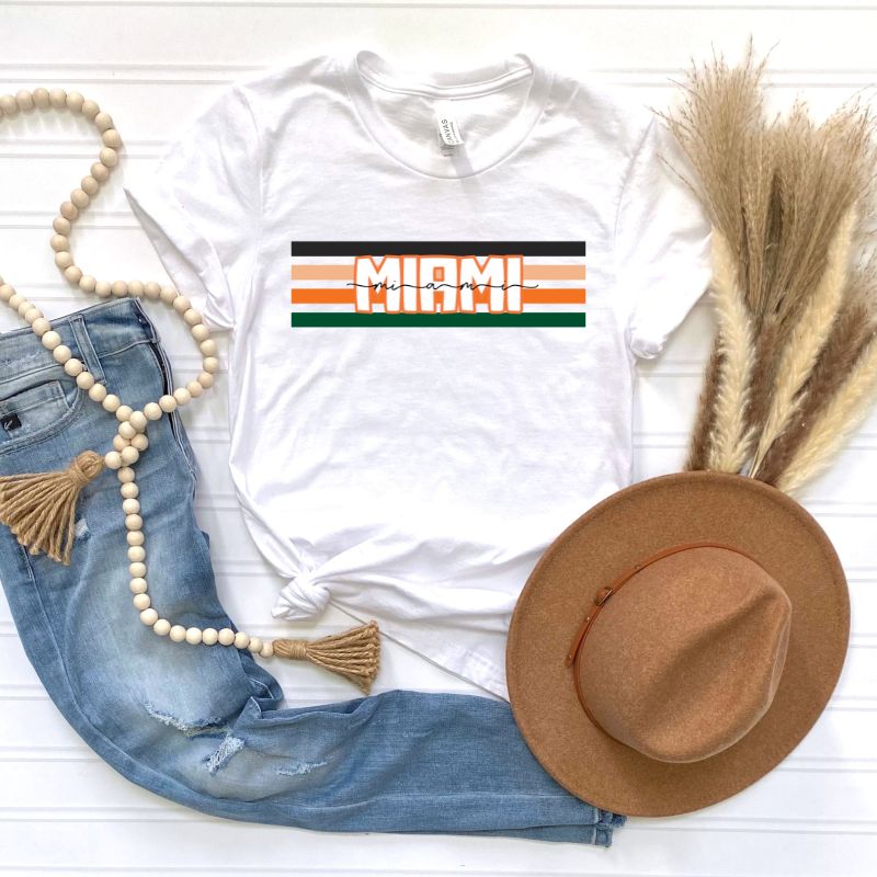 Bella + Canvas 3001 unisex t-shirt featuring the University of Miami design with black, orange, and green stripes and "Miami" text in the center on a white shirt.