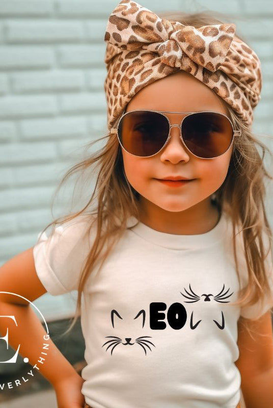 Purr-fectly adorable! Our kids' shirt features the word 'meow' creatively designed with cat ears for the M and upside-down cat ears for the W on a white shirt. 
