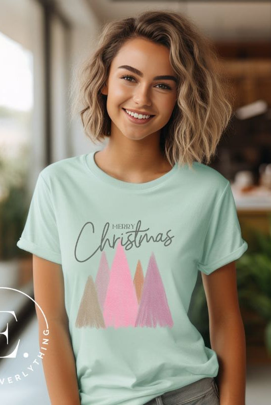 Get into the holiday spirit with our modern minimalist Christmas t-shirt. It features charming pastel Christmas trees with a sleek "Merry Christmas" message above the trees, perfectly blending simplicity and festive cheer on a mint shirt. 