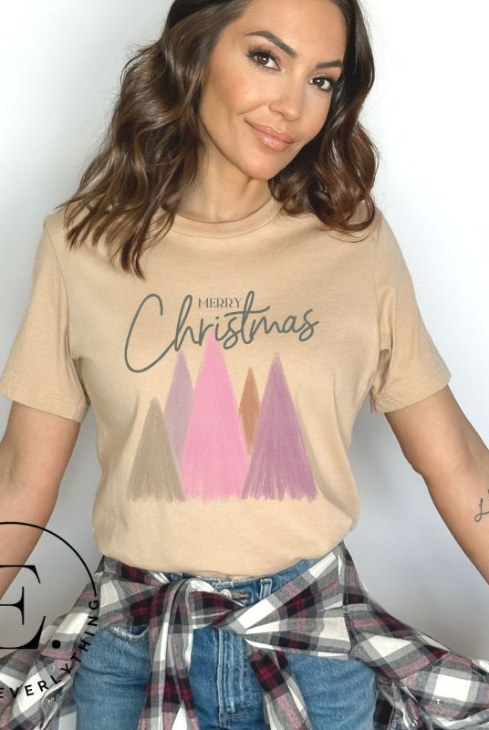 Get into the holiday spirit with our modern minimalist Christmas t-shirt. It features charming pastel Christmas trees with a sleek "Merry Christmas" message above the trees, perfectly blending simplicity and festive cheer on a tan shirt. 