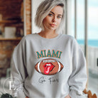Show off your Miami Dolphins pride with this eye-catching sweatshirt, boasting a football and playful lips and tongue design. Highlighted with the team's motivating slogan "Go Fins" and the iconic Miami wordmark, on a grey sweatshirt. 