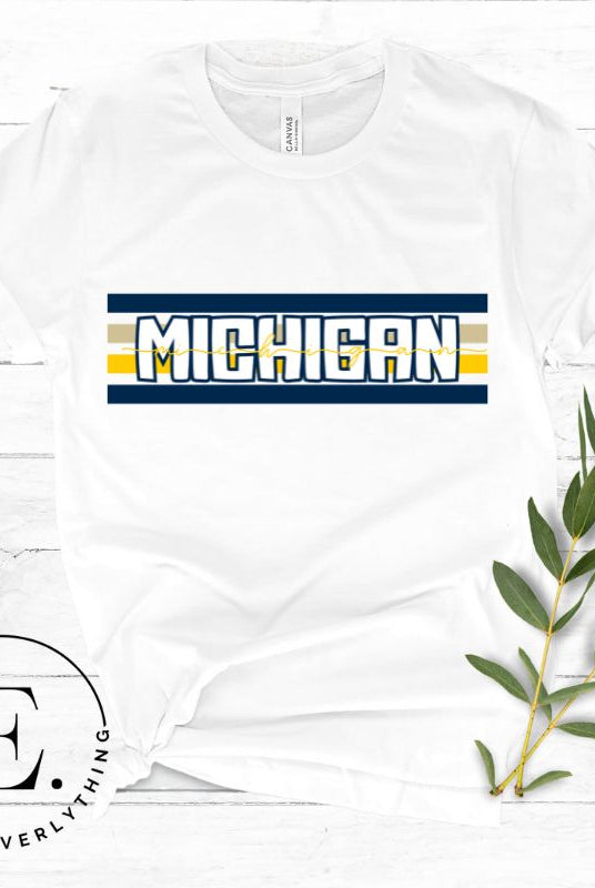 Elevate your collegiate style with our Michigan University graphic tee featuring iconic school colors and bold chest stripes. Emblazoned with "Michigan" in striking lettering, on a white shirt. 