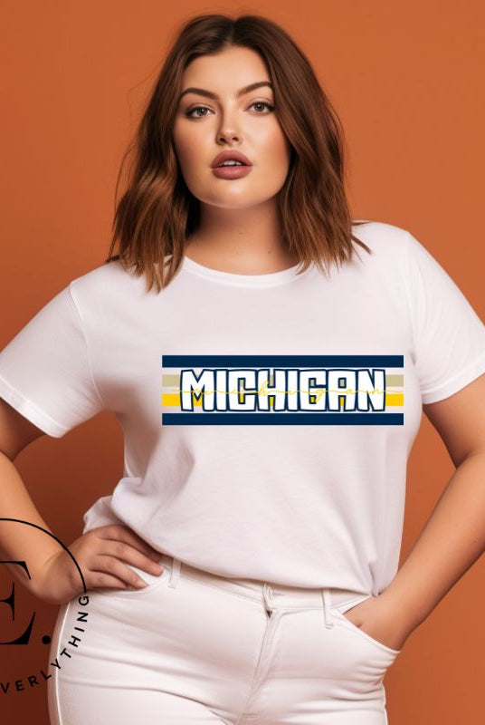 Elevate your collegiate style with our Michigan University graphic tee featuring iconic school colors and bold chest stripes. Emblazoned with "Michigan" in striking lettering, on a white shirt. 