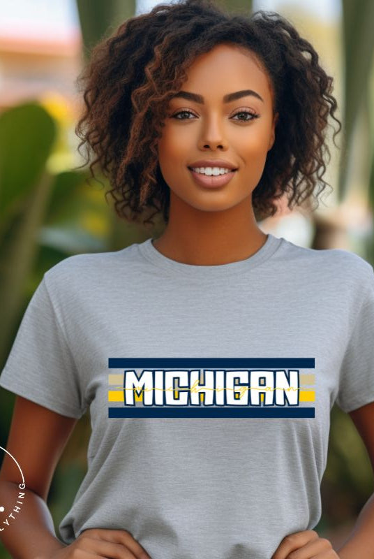 Elevate your collegiate style with our Michigan University graphic tee featuring iconic school colors and bold chest stripes. Emblazoned with "Michigan" in striking lettering, on a grey shrit. 