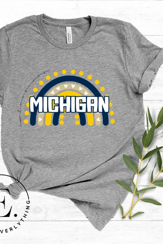 Unleash your vibrant spirit with our Michigan graphic tee. Adorned with a rainbow in school colors and "Michigan" in playful block bubble lettering, this shirt exudes energy and Wolverine pride on a grey shirt. 