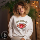 Get ready to represent the New Orleans Saints in style with this vibrant sweatshirt. Featuring a football and playful lips and tongue design, it proudly displays the team's iconic slogan "Who Dat" and the distinctive New Orleans wordmark on a white sweatshirt. 