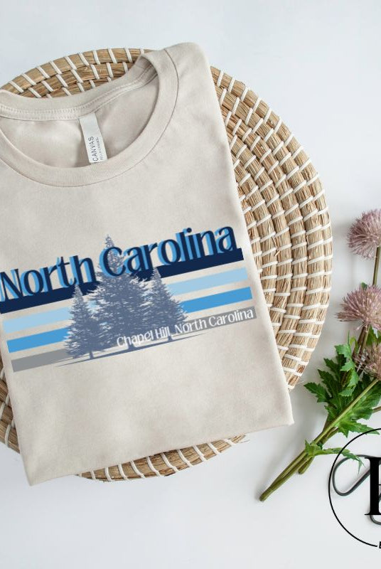Show your school pride with this iconic North Carolina wordmark t-shirt. Made from premium materials, it features a North Carolina tree line in a the cool Carolina blue colors, representing a tradition of excellence for the nature that North Carolina offers on a sand colored shirt. 