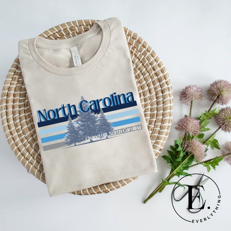 Show your school pride with this iconic North Carolina wordmark t-shirt. Made from premium materials, it features a North Carolina tree line in a the cool Carolina blue colors, representing a tradition of excellence for the nature that North Carolina offers on a sand colored shirt. 