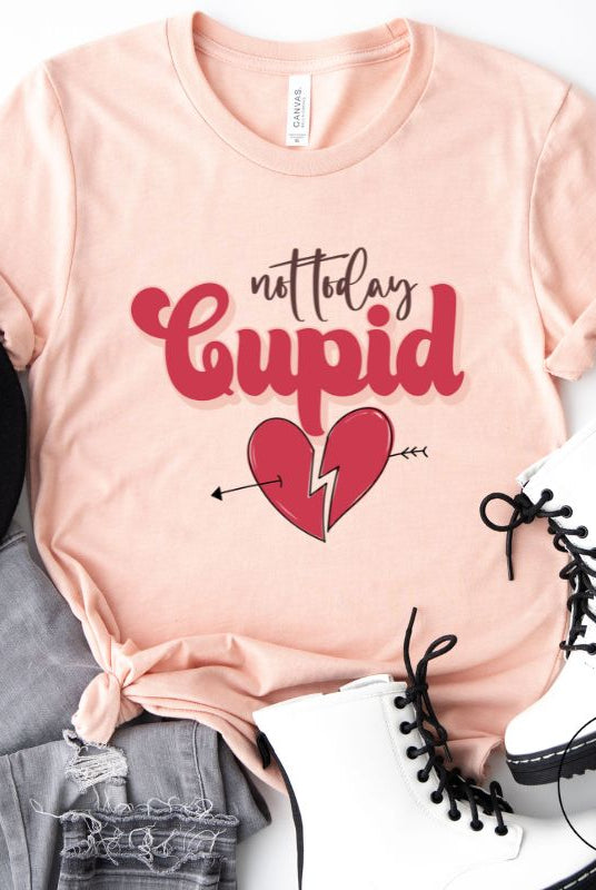 Spice up your Valentine's Day with our edgy shirt featuring a broken heart pierced by an arrow, and the defiant phrase "Not Today Cupid" on a peach shirt. 