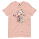 Peach t-shirt featuring a detailed skeleton design with ribcage and hands intertwined with soft, colorful flowers, blending gothic and floral aesthetics.