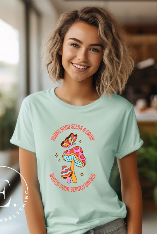 Embrace the beauty of nature with our mushroom and butterfly shirt. Featuring a captivating design of a mushroom and butterfly, it symbolizes growth and transformation. With the inspiring message "Plant your seed and grow watch your beauty unfold," on a mint shirt. 