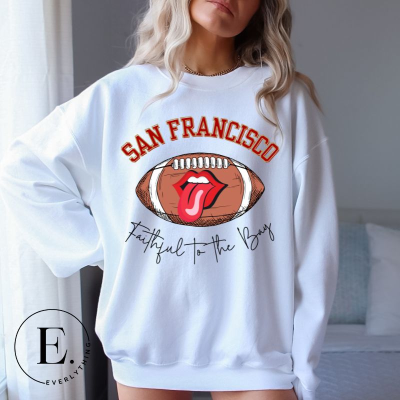 Show you allegiance to the San Francisco 49ers with this trendy sweatshirt, featuring a football and playful lips and tongue design. Emblazoned with the team's slogan "Faithful to the Bay" and the iconic San Francisco wordmark, on a white sweatshirt. 