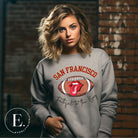 Show you allegiance to the San Francisco 49ers with this trendy sweatshirt, featuring a football and playful lips and tongue design. Emblazoned with the team's slogan "Faithful to the Bay" and the iconic San Francisco wordmark, on a grey sweatshirt. 