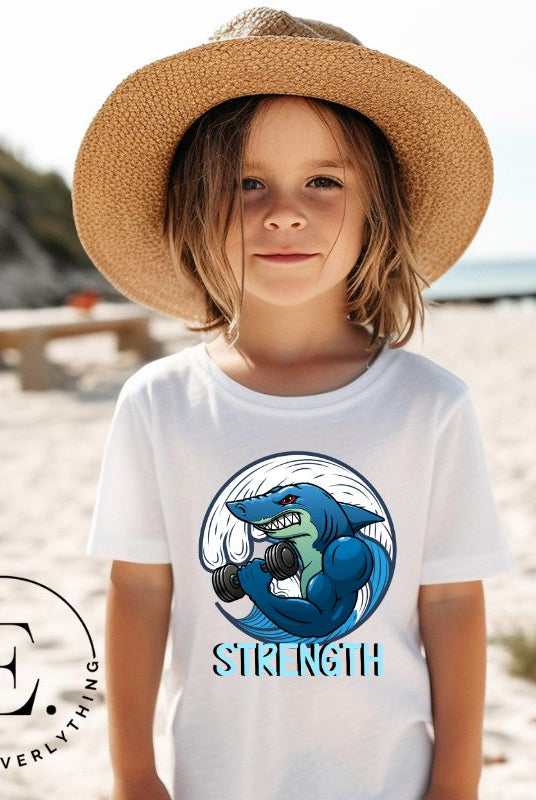 Dive into strength and style with our kids' shirt. Featuring a shark lifting weights with the empowering word 'strength' underneath on a white shirt. 